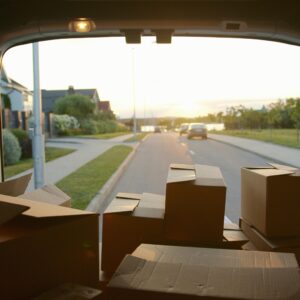 A scenic view from a delivery van loaded with cardboard boxes at sunset on a suburban street.